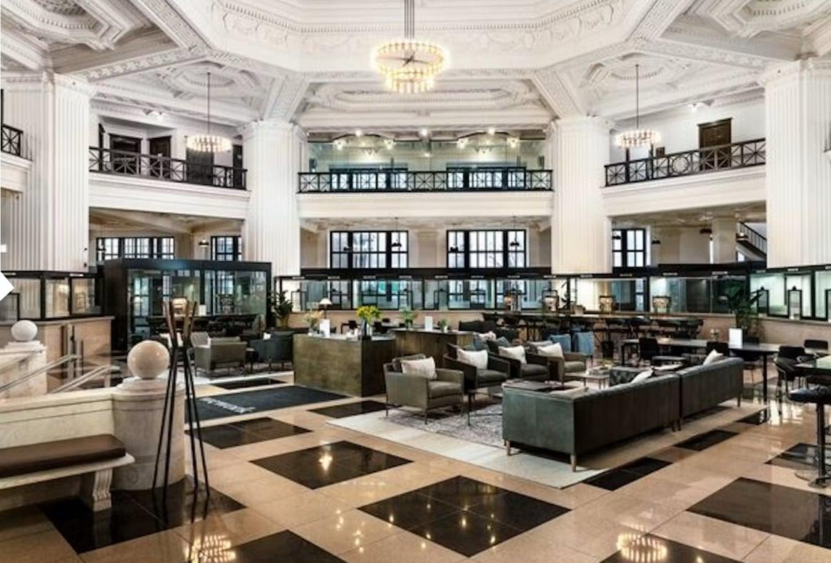 A grand hall with marble floors, a coffered ceiling and lounge seating